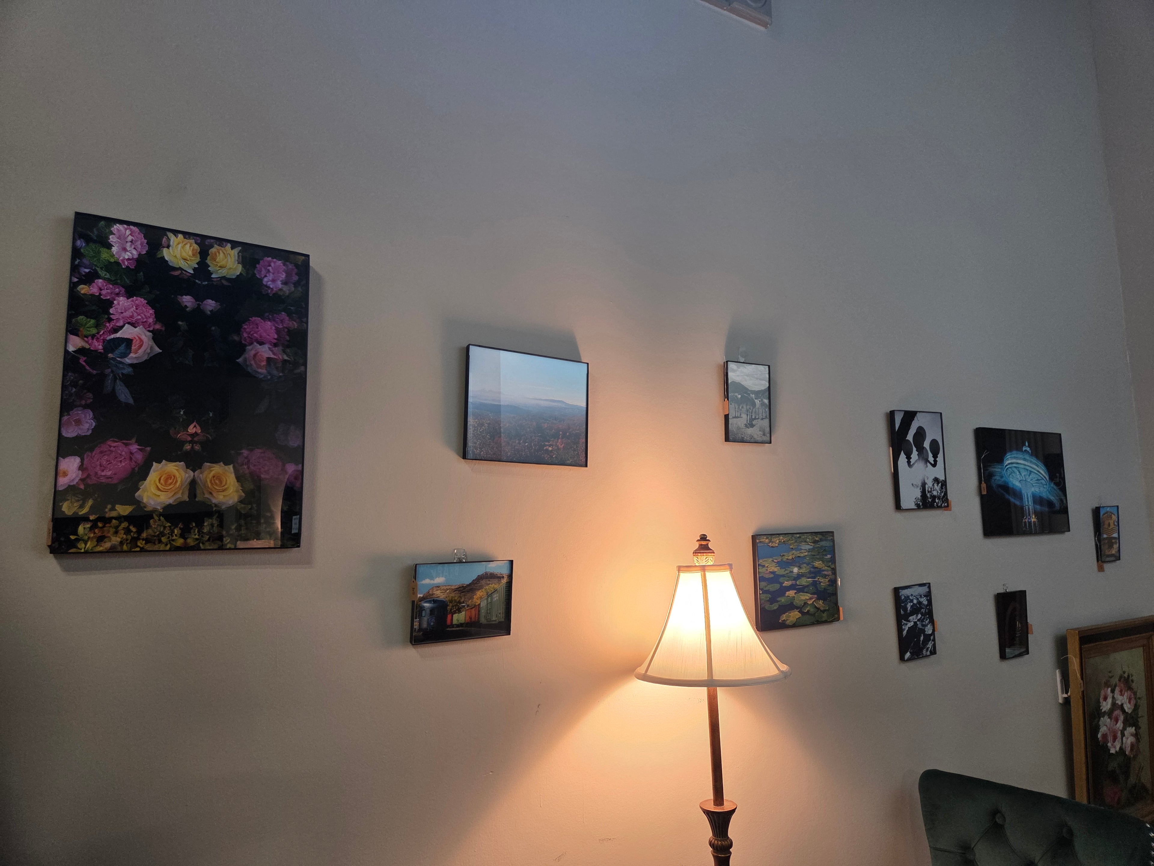 Wall with various framed pictures and a lamp casting light on the wall.