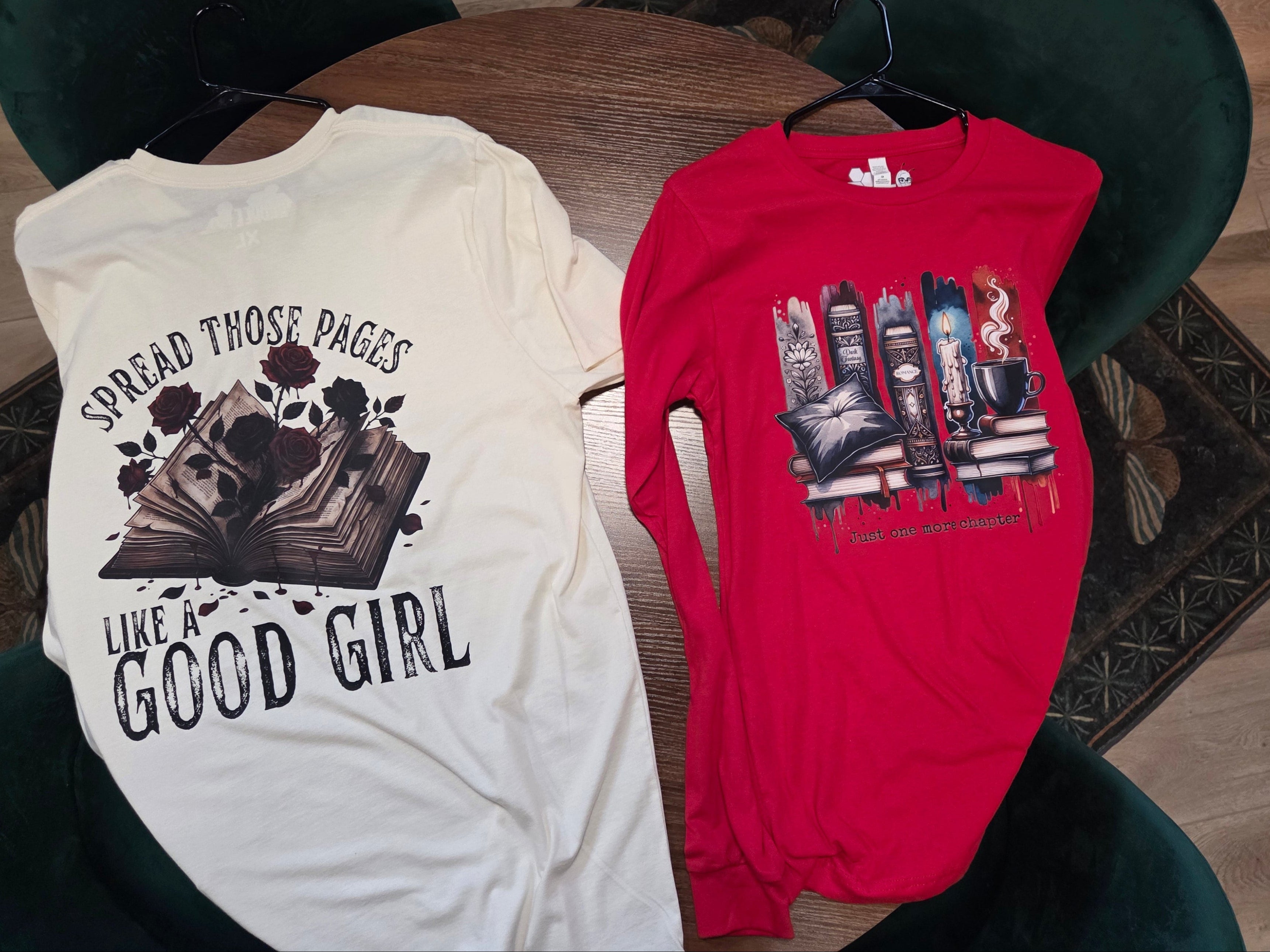Two t-shirts on a table with one white and one red, featuring text and graphics.