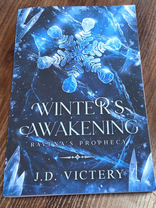 Book titled 'Winter's Awakening' by J.D. Victery on a wooden surface
